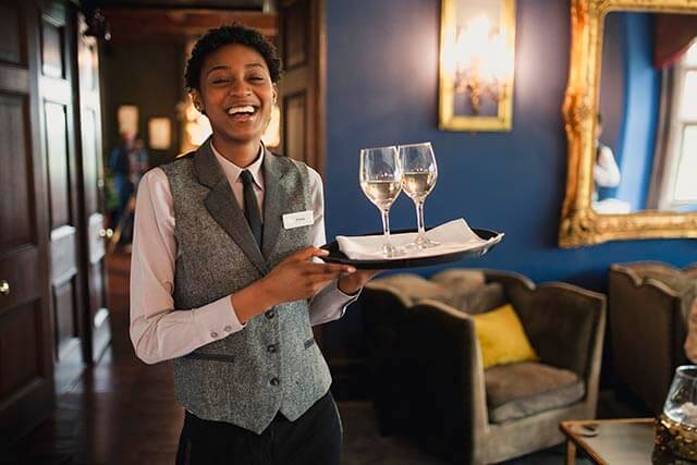 Hotel employee carrying wine glasses on a tray